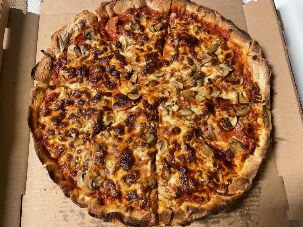 Large sausage and mushroom pizza in a cardboard box